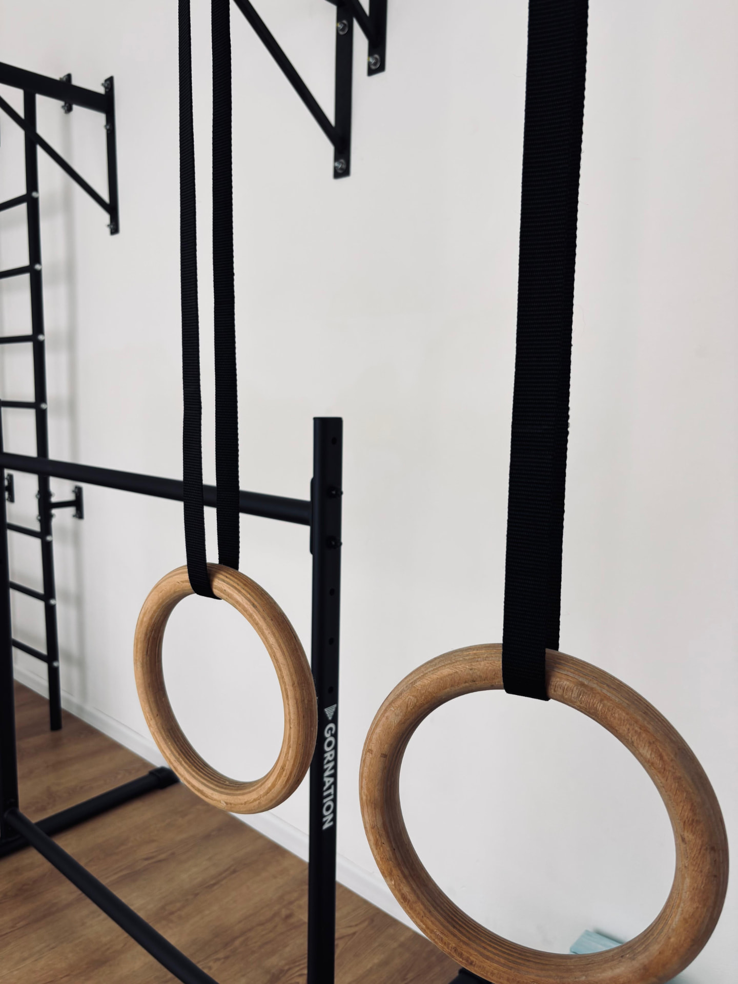 Anelli di legno per calisthenics appesi a cinghie nere nello studio Feel Good
