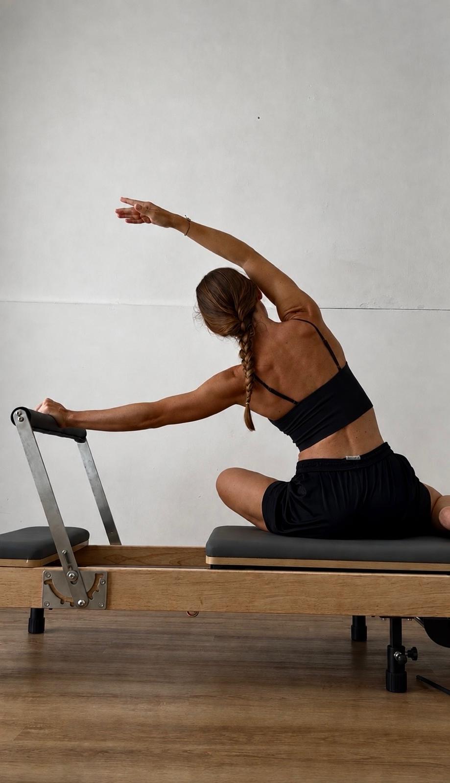 Istruttrice che esegue un esercizio di stretching sul reformer nello studio Feel Good